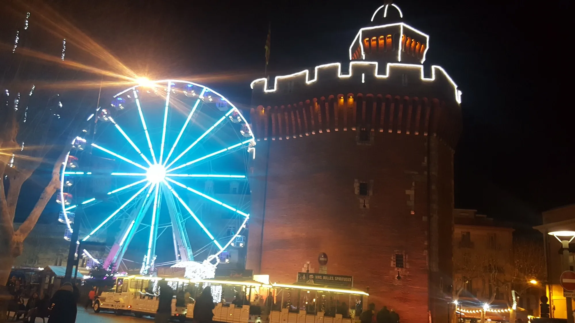 Le Castillet de Perpignan illuminé pour Noël, avec la grande roue du marché de Noël